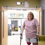 Amputee client, Sharon stands in the entrance to the gym at STEPS Rehabilitation